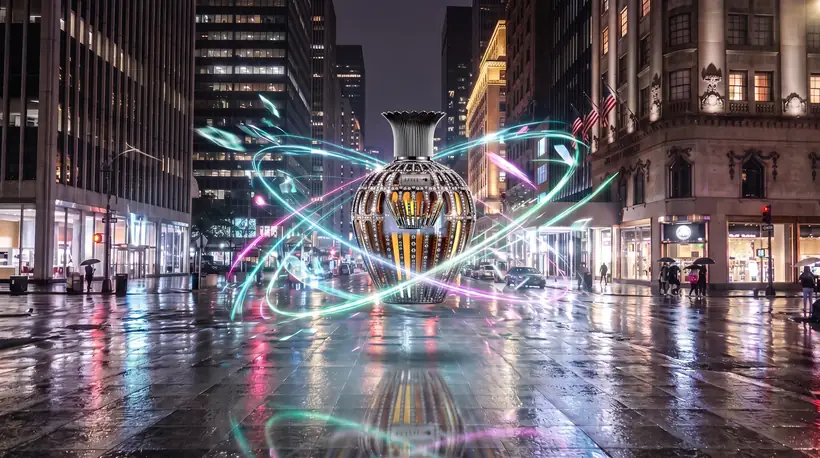 A giant crystal-caged perfume flacon hovering above a rain-wet pedestrian plaza at night, cyan electric filaments arcing around it between lit shopfronts